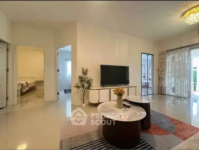 Spacious living room with modern decor and large TV, adjacent to bedroom and outdoor area.