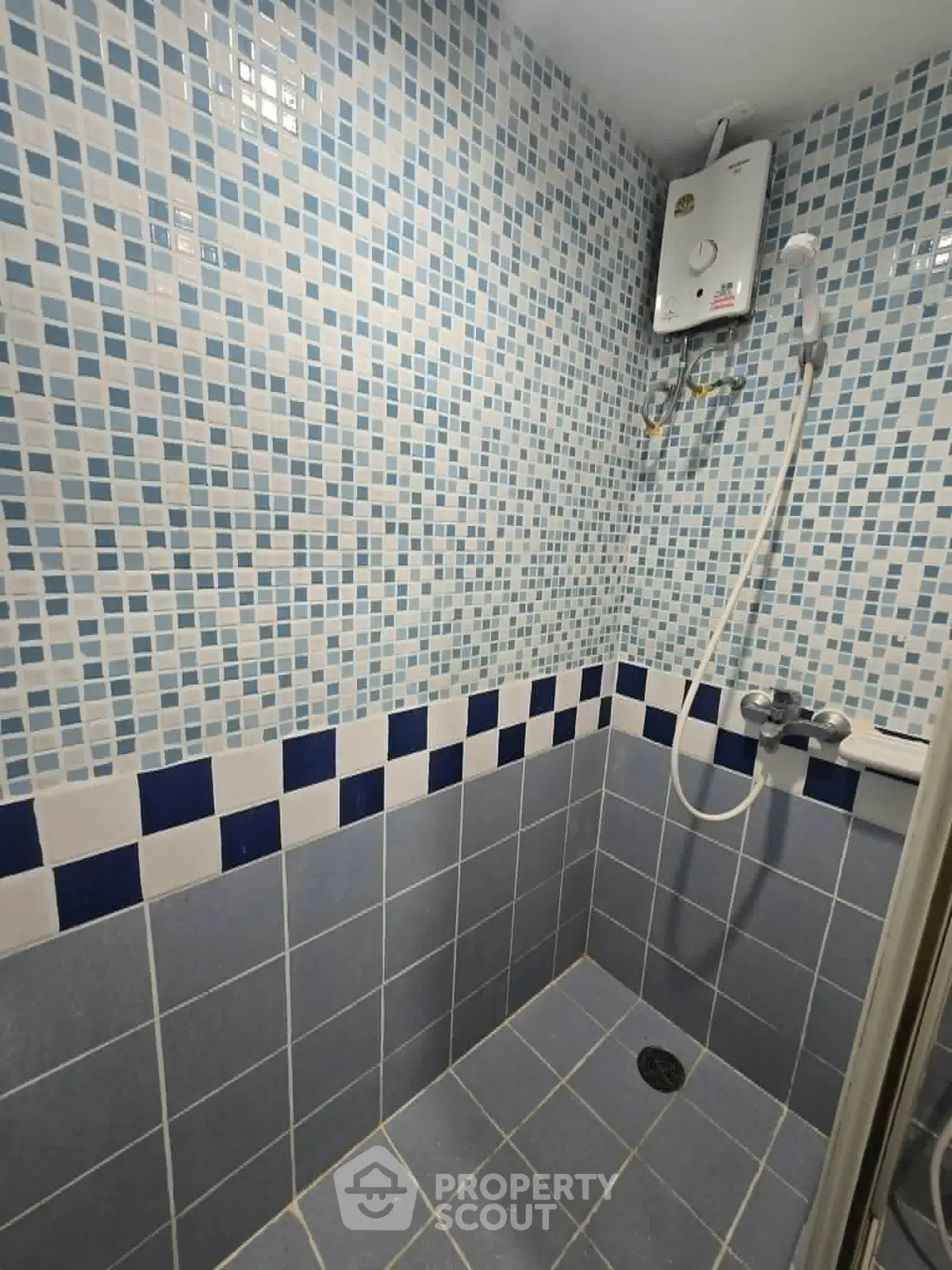 Modern bathroom with tiled walls and electric shower unit, perfect for compact living spaces.