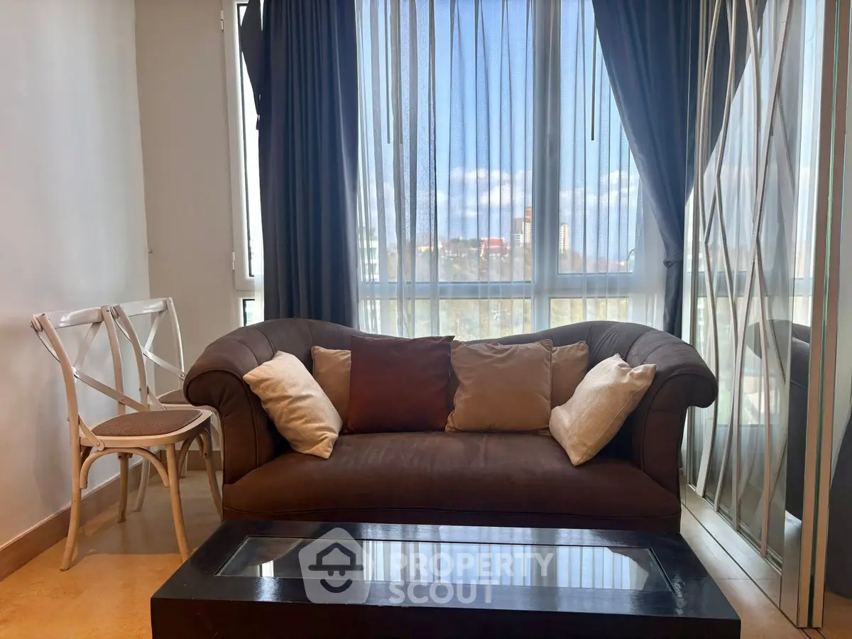 Cozy living room with stylish sofa and large window offering a bright city view.