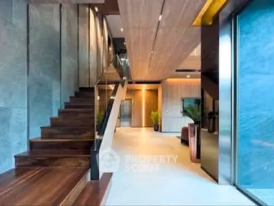 Luxurious modern interior with wooden staircase and open living area, showcasing elegant design and spacious layout.
