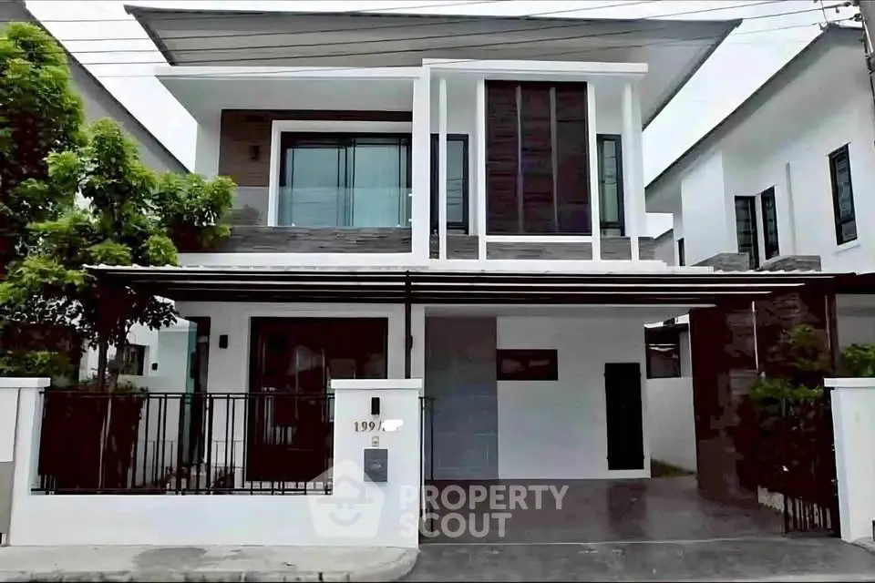 Modern two-story house with sleek design and spacious balcony in a suburban neighborhood.