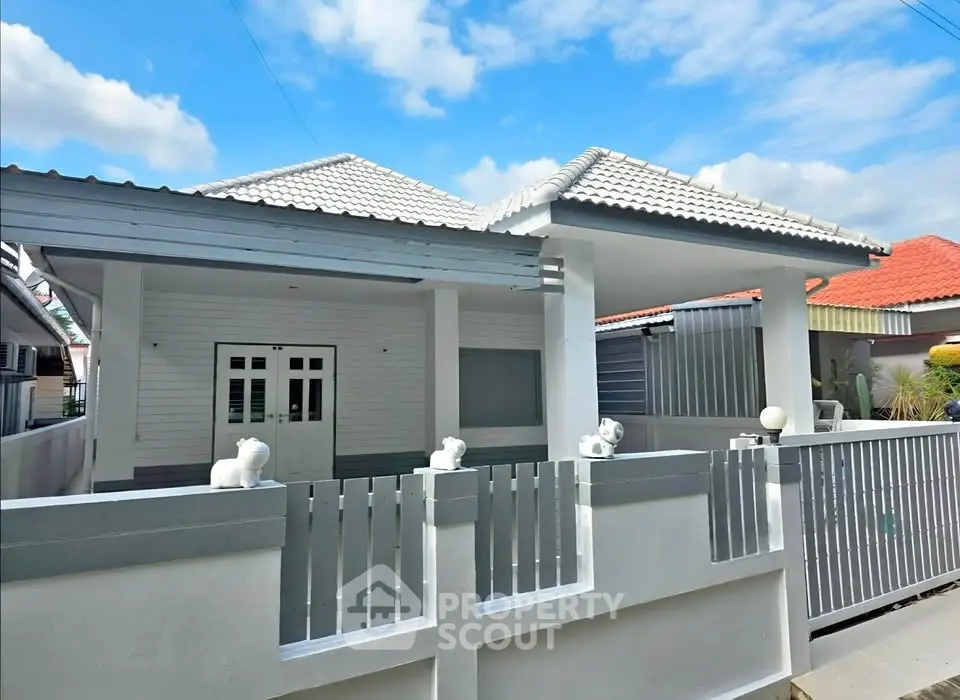 Charming single-story home with white picket fence and tiled roof under a clear blue sky.