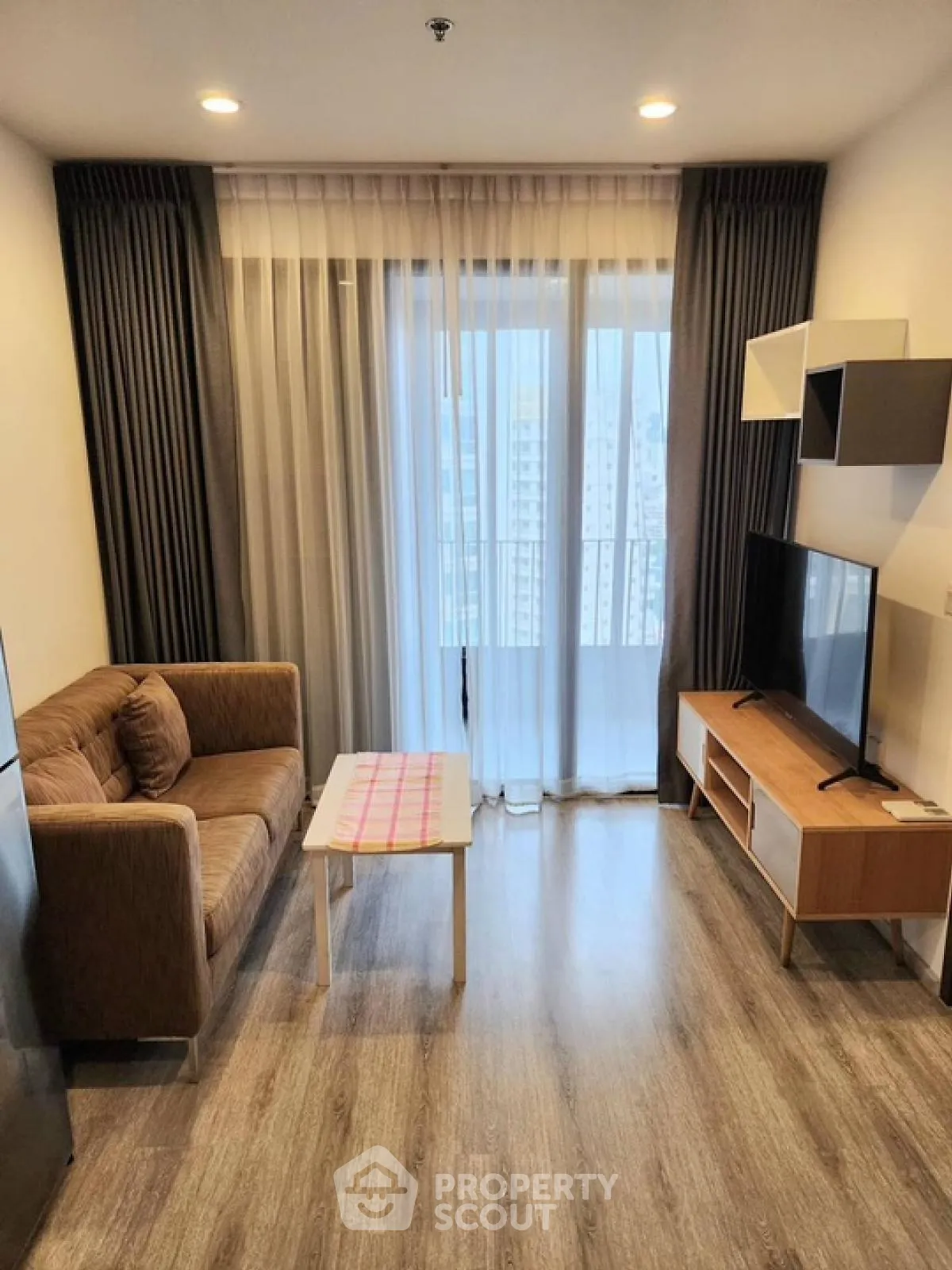 Modern living room with cozy sofa, TV, and large window view.