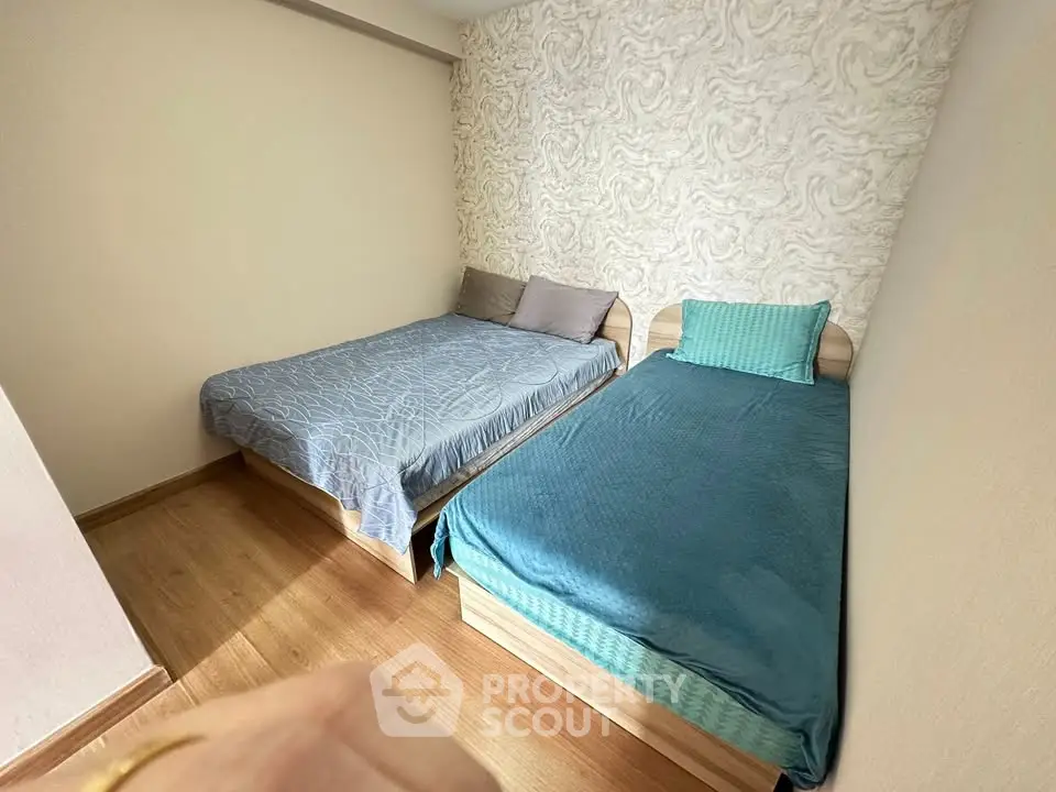 Cozy bedroom with two beds and stylish wallpaper, perfect for a comfortable stay.