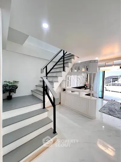 Modern interior with sleek staircase and open living area, featuring elegant design and natural light.