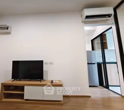 Modern living room with sleek TV stand and air conditioning, adjacent to a compact kitchen.