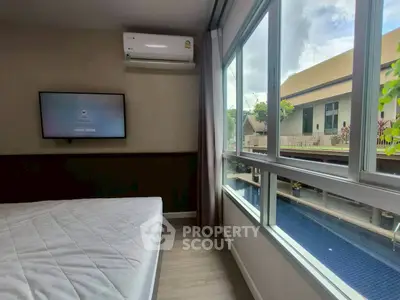 Modern bedroom with pool view and wall-mounted TV in a stylish apartment.