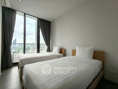 Modern bedroom with twin beds and city view from large windows