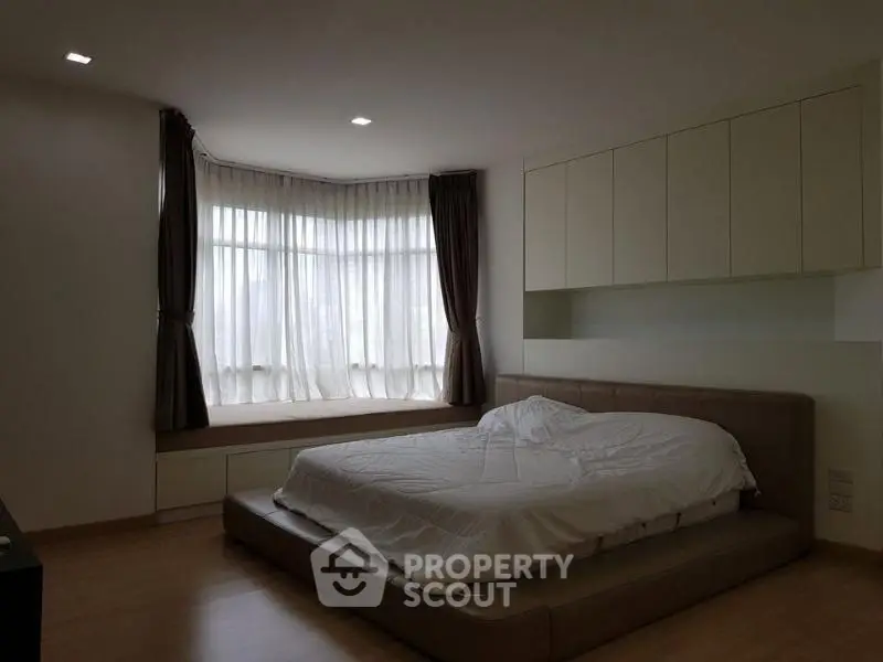 Spacious bedroom with modern design and large window seating area.