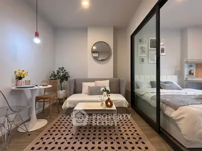 Modern studio apartment with cozy living area and stylish bedroom separated by glass partition.