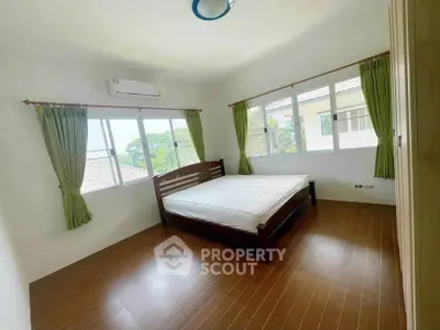 Bright bedroom with large windows and wooden flooring in a modern home.
