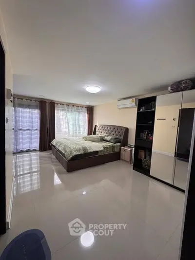 Spacious bedroom with modern decor and large windows for natural light.