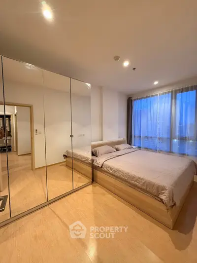 Spacious bedroom with mirrored wardrobe and large window offering serene views.