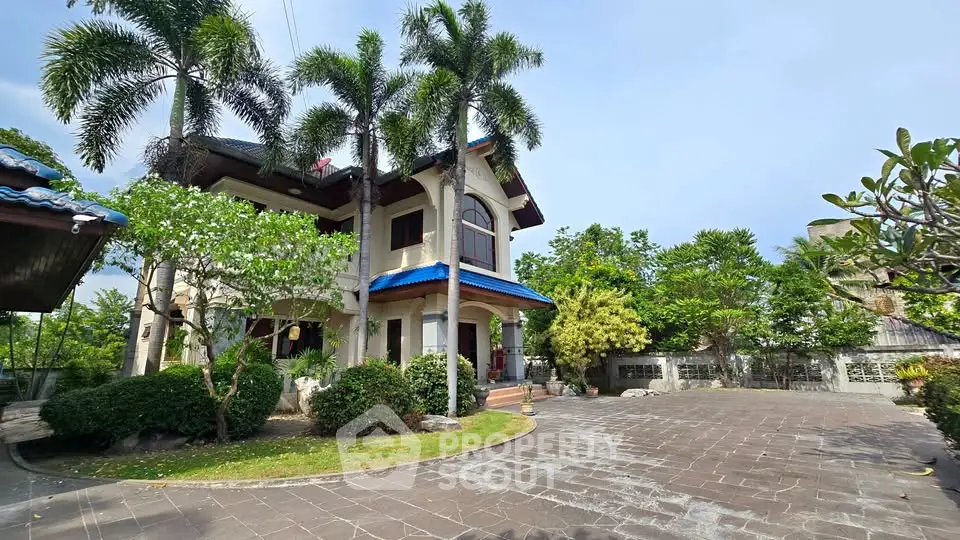 Stunning two-story house with lush garden and spacious driveway, featuring tropical landscaping and elegant architecture.