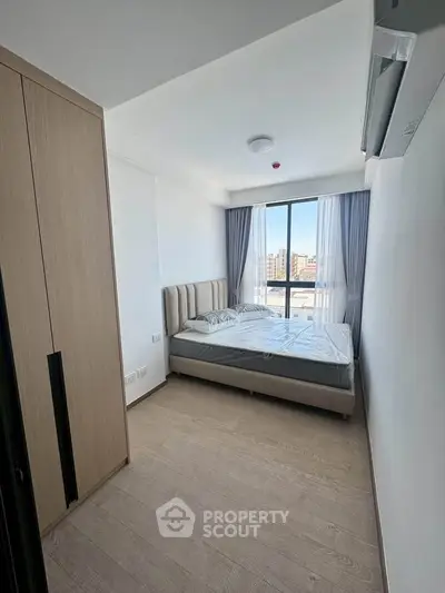 Modern bedroom with large window and stylish furnishings in a bright apartment.