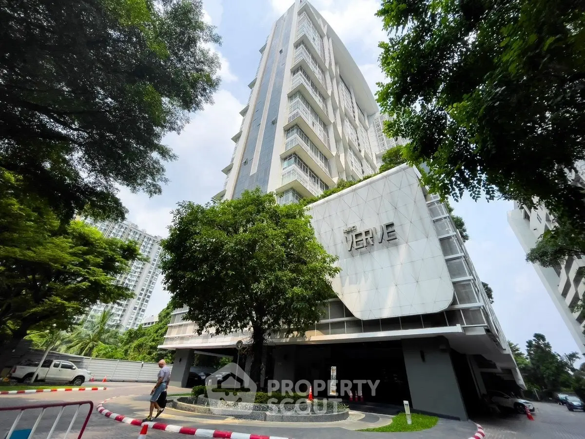 Modern high-rise building with lush greenery and sleek architectural design.