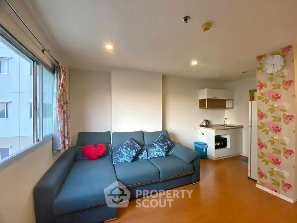 Cozy living room with modern sofa and compact kitchen in open layout apartment.