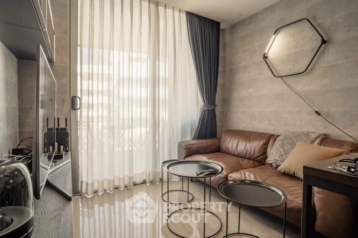 Modern living room with leather sofa and stylish decor, featuring floor-to-ceiling windows and elegant curtains.