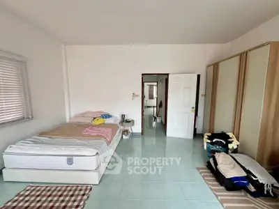 Spacious bedroom with minimalist decor and ample natural light, featuring a comfortable bed and large wardrobe.