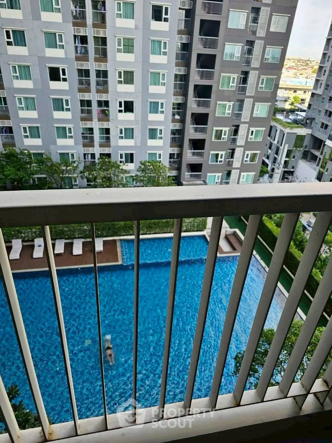 Modern apartment balcony view overlooking a luxurious swimming pool and high-rise buildings.