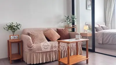 Cozy living room with plush sofa and view into elegant bedroom