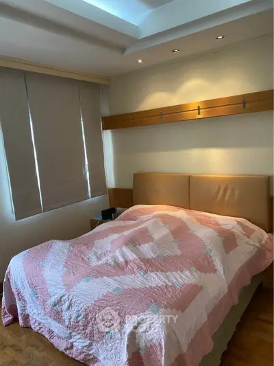 Cozy bedroom with stylish quilt and modern lighting, perfect for restful nights.