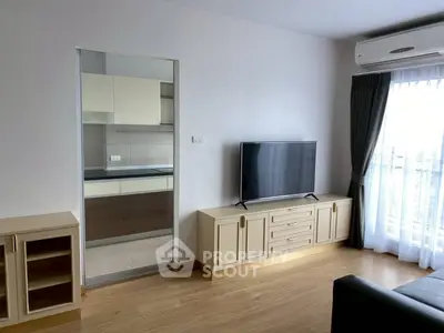Modern living room with sleek TV unit and view into stylish kitchen