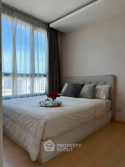 Cozy bedroom with large window and elegant decor, perfect for relaxation and comfort.