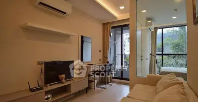 Modern living room with balcony and study area, featuring sleek furniture and natural light.