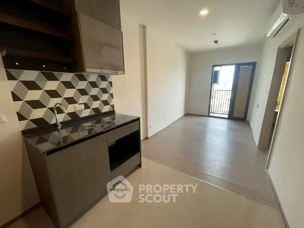 Modern apartment with sleek kitchen and open living space leading to a balcony.
