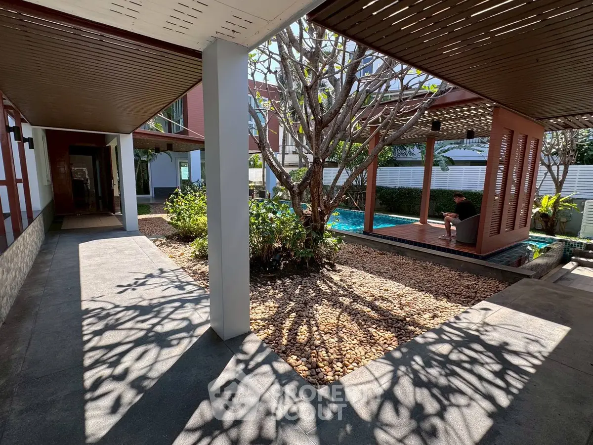 Modern residential complex with poolside relaxation area and lush greenery.