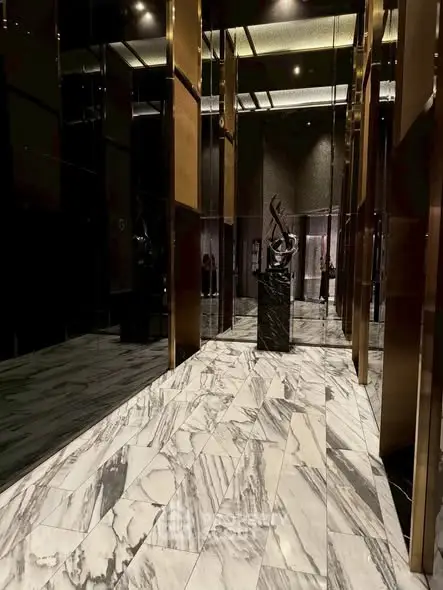 Luxurious building entrance with marble flooring and modern sculpture