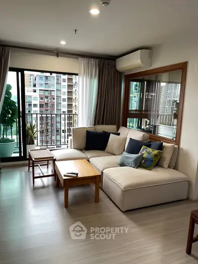 Modern living room with large windows and city view, featuring cozy seating and stylish decor.