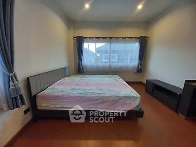Spacious bedroom with large windows and elegant curtains, featuring a modern bed and wooden flooring.
