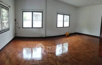 Spacious empty room with polished wooden floors and large windows