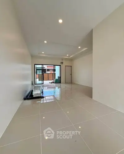 Spacious modern living room with glossy tiled floors and large windows for natural light.
