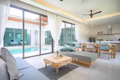 Luxurious open-plan living room with pool view, modern furniture, and elegant decor in a contemporary home.