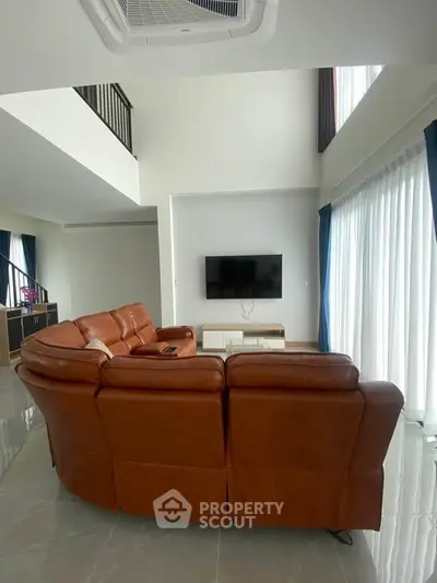 Spacious living room with high ceilings and modern leather sofa, perfect for relaxation and entertainment.