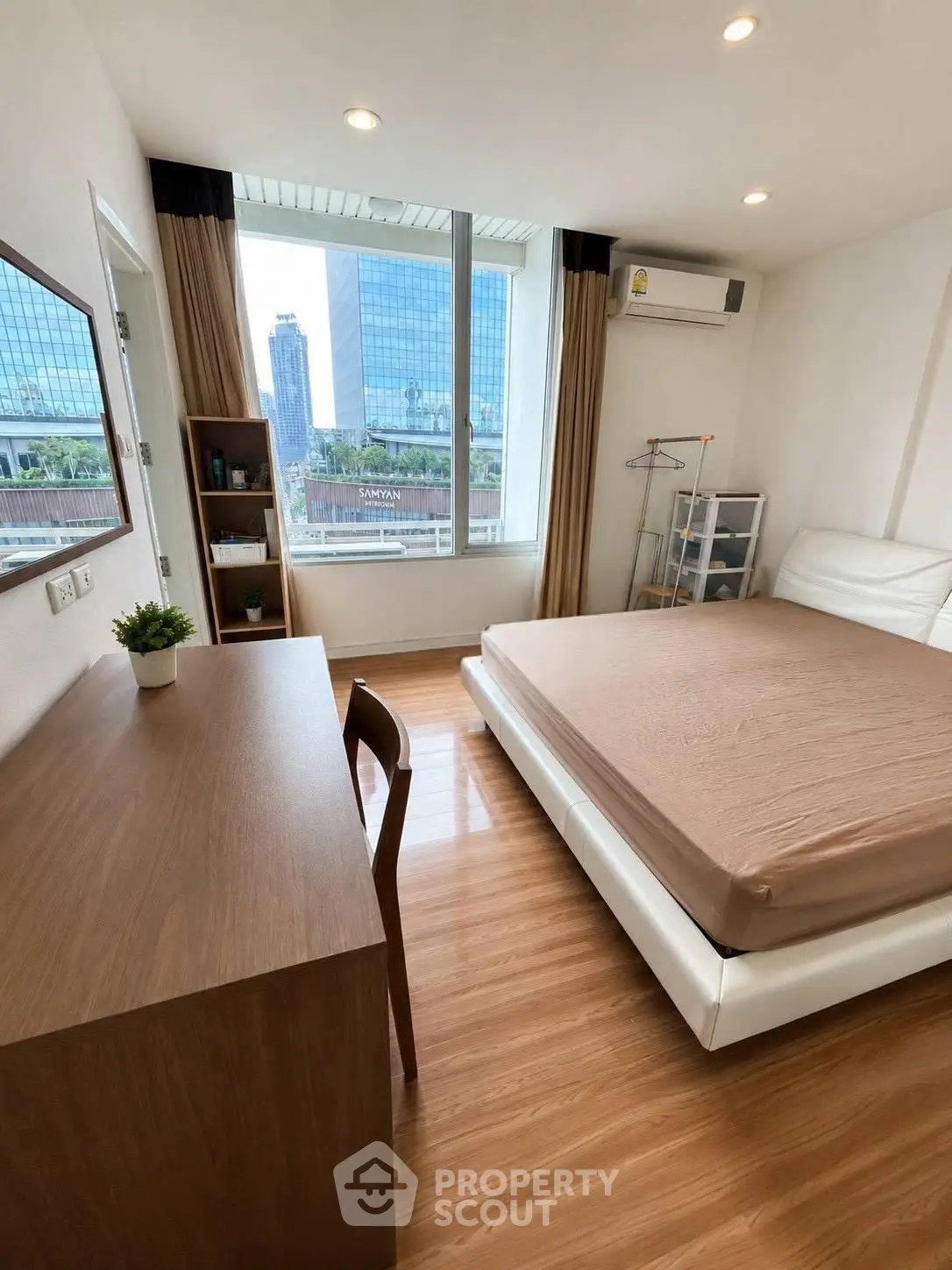 Modern bedroom with city view, featuring sleek furniture and large window for natural light.
