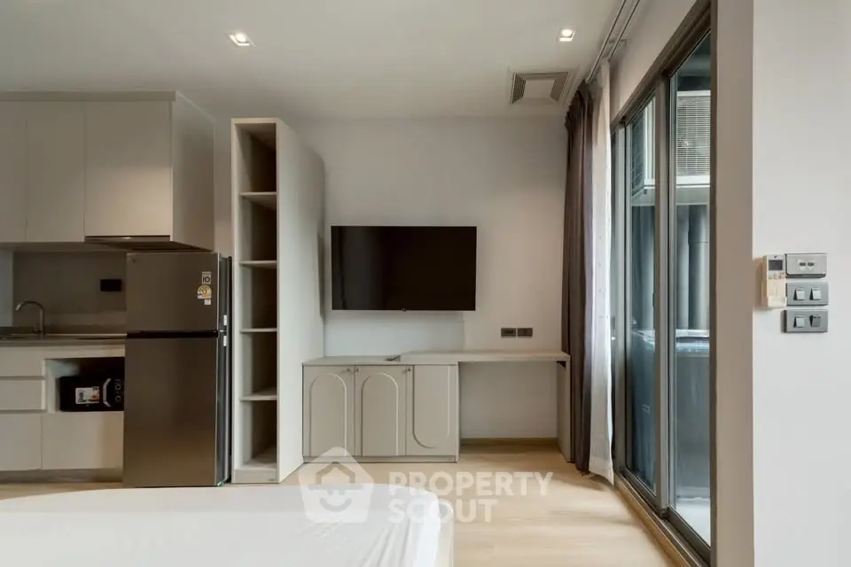 Modern studio apartment with sleek kitchen and large window for natural light.