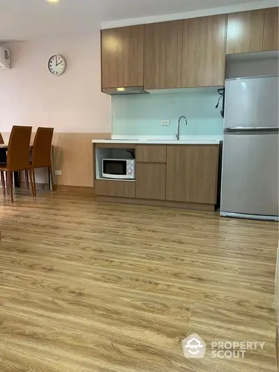 Modern kitchen with wooden flooring, microwave, and fridge in a cozy dining area.