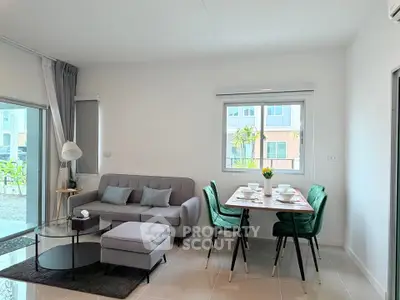Modern living room with stylish furniture and dining area, featuring large windows and natural light.
