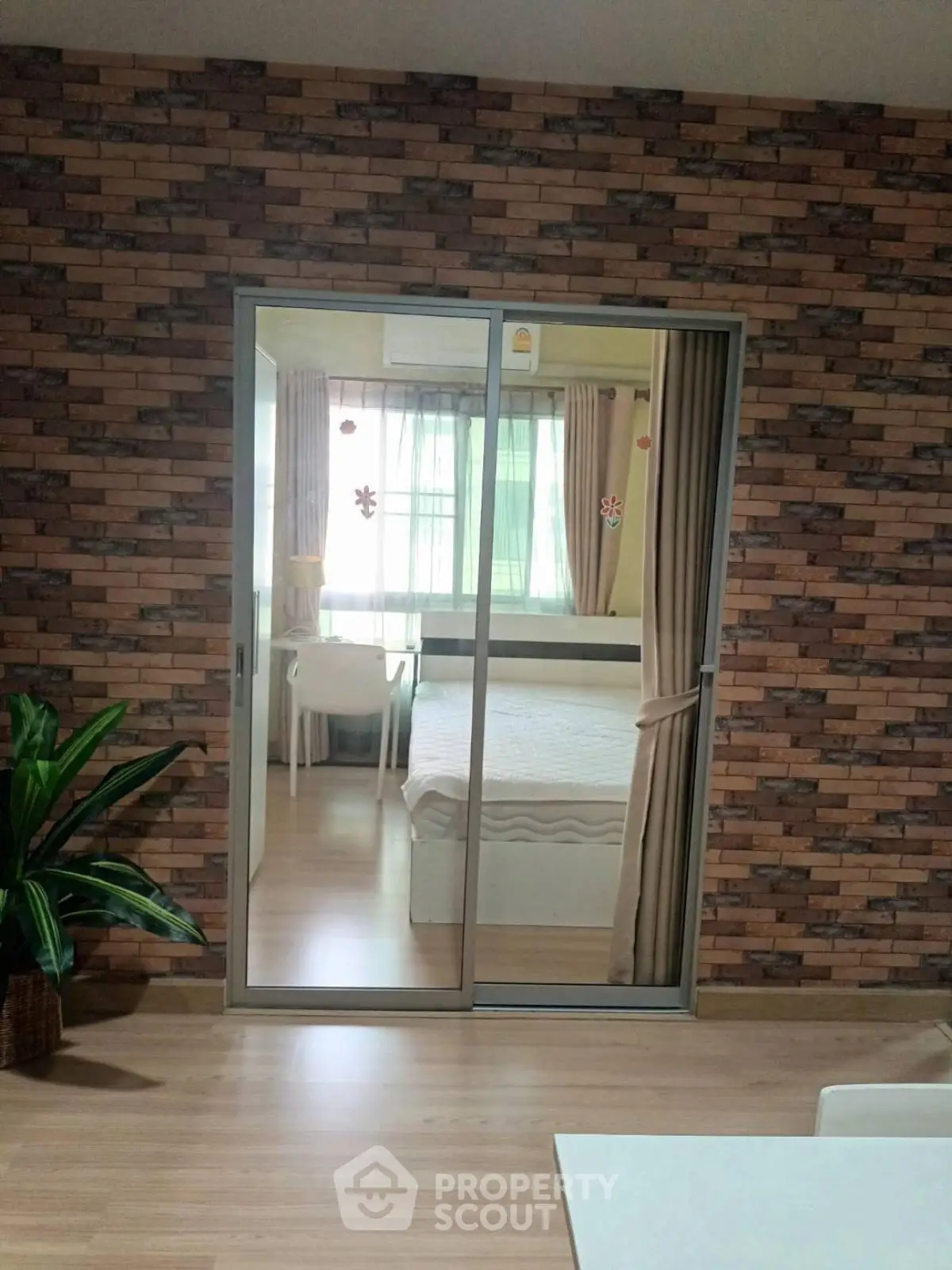 Modern bedroom with sliding glass doors and stylish brick accent wall.
