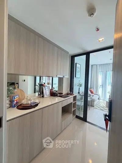 Modern kitchen with sleek cabinetry and open layout leading to a bright living area.