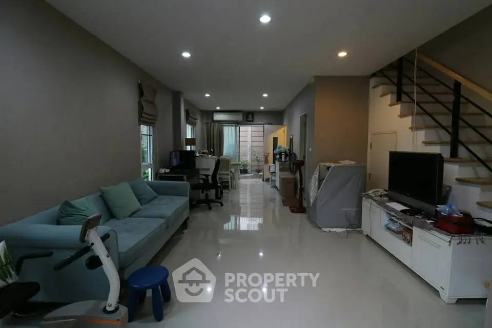 Spacious living room with modern decor and sleek staircase in a contemporary home.