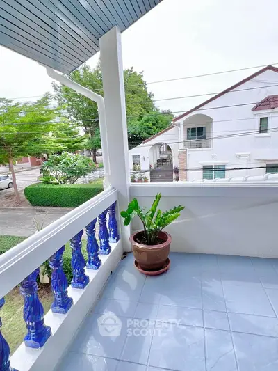 Charming balcony with blue railings and potted plant overlooking suburban street view.