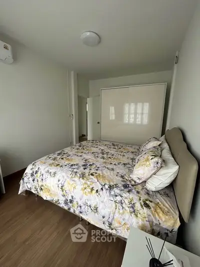 Cozy bedroom with floral bedding and ample closet space in modern apartment.