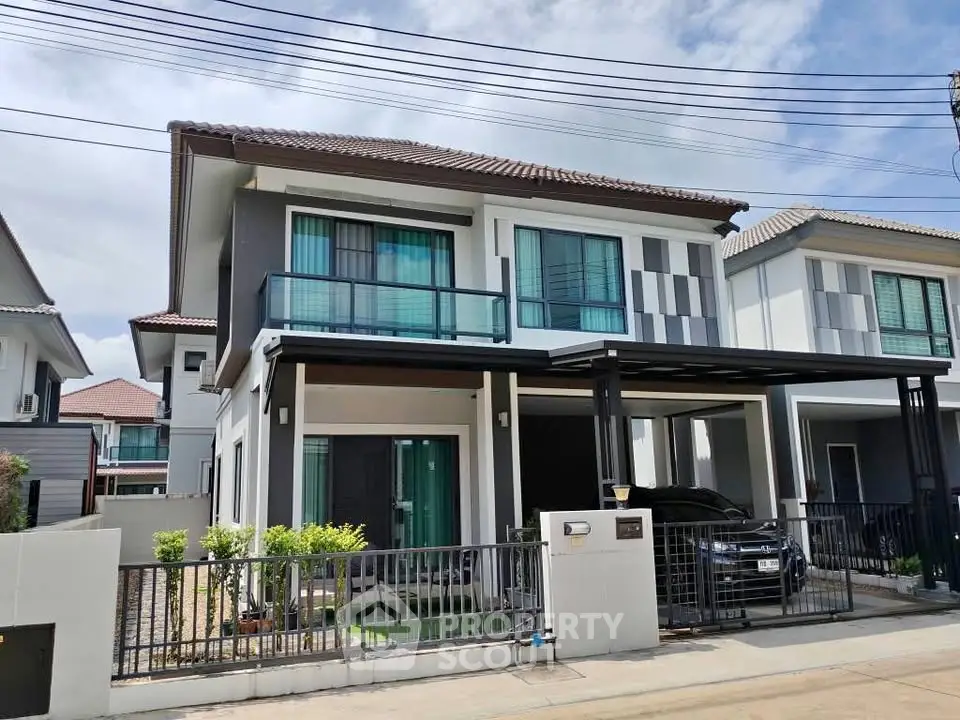 Modern two-story house with sleek design and spacious driveway in a suburban neighborhood.