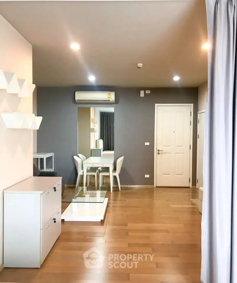 Modern living room with wooden flooring, stylish furniture, and air conditioning in a cozy apartment.