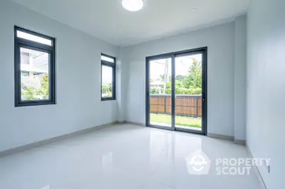 Bright empty room with large windows and garden view, perfect for customization.